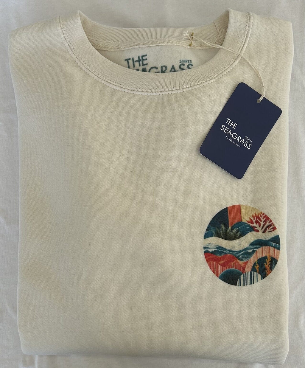 Fotografía real de la sudadera ARRECIFE Vintage doblada con etiqueta The Seagrass Shirts.