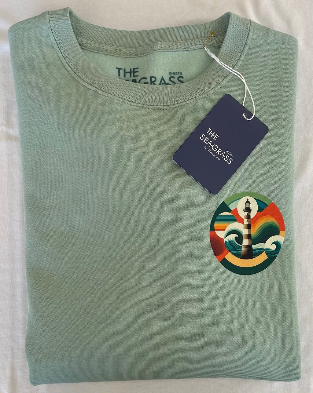 Fotografía real de la sudadera FARO Sage doblada con etiqueta The Seagrass Shirts.